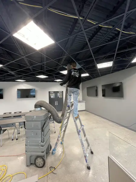 Commercial air duct cleaning setup with vacuum equipment in an open office space