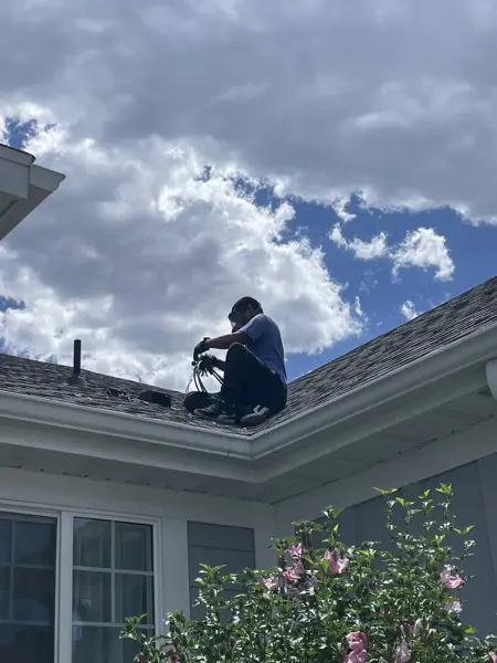 Technician cleaning a rooftop vent on a two-story home